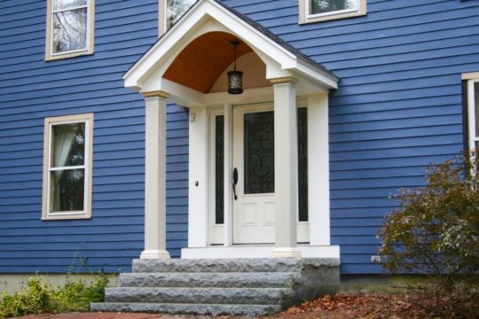 Royal blue painted exterior siding on house with white door/awning addition