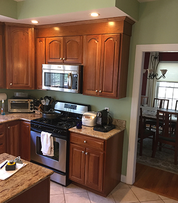 Kitchen with dark brown cabinets, green walls, and silver appliances