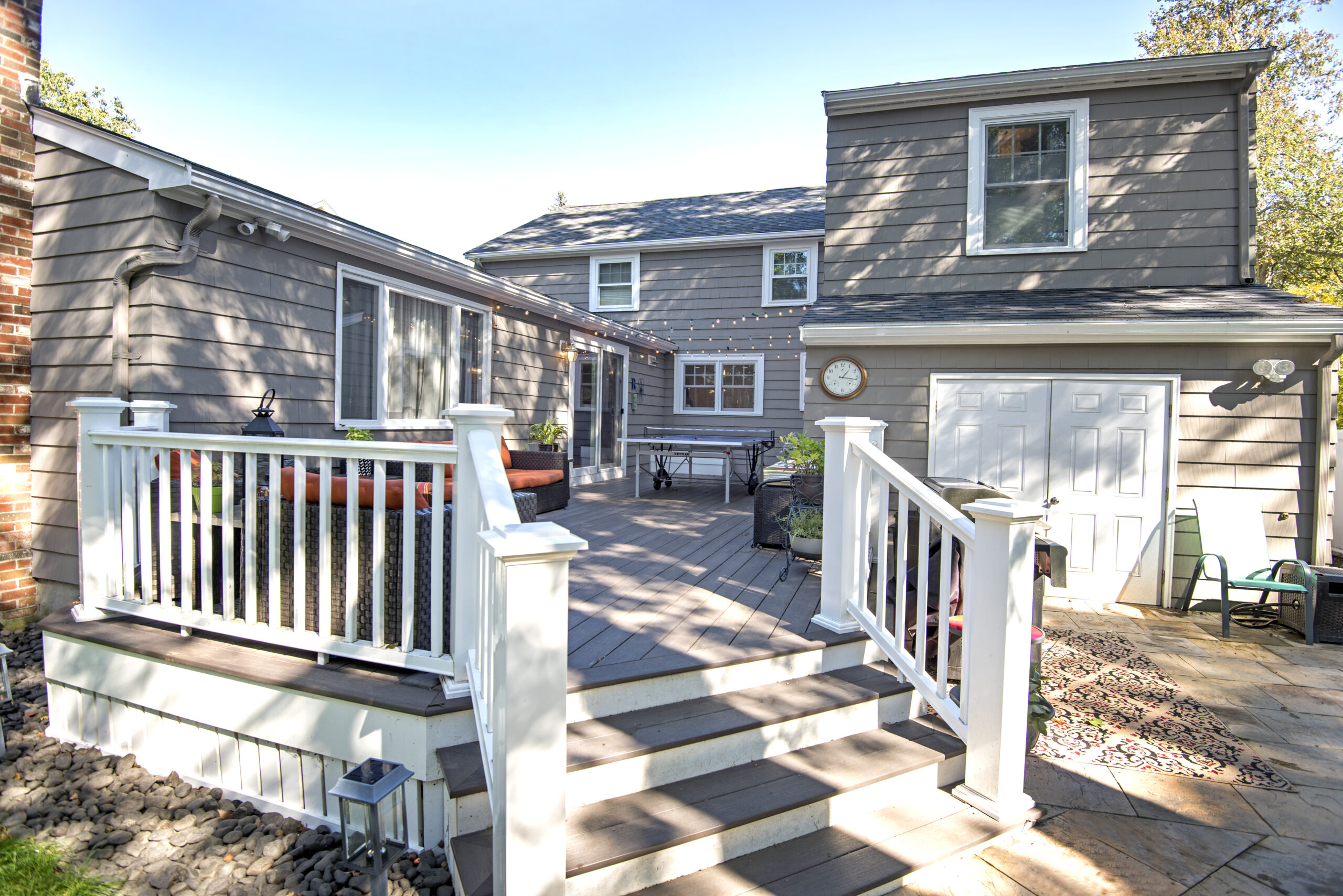 Grey house with large exterior back deck addition and string lights