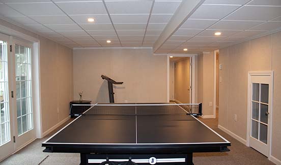 Finished basement with french doors leading outside and ping pong table in the center