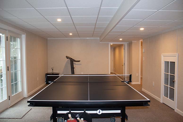 Finished basement with french doors leading outside and ping pong table in the center