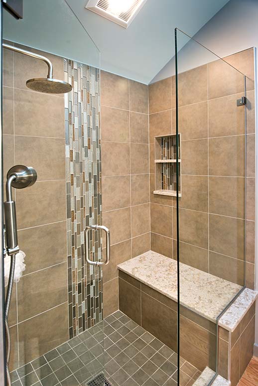 Ceramic tiled shower with bench, built-in shelves, and glass rectanglular tiled accents