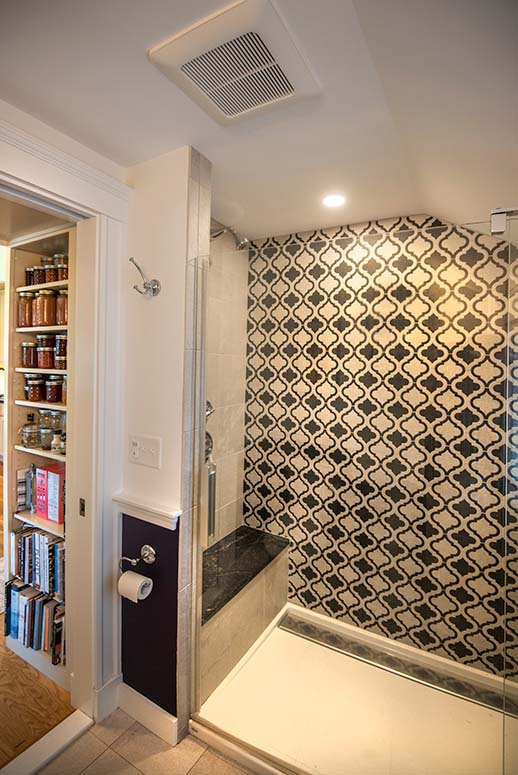 Large walk-in shower with marble-topped bench and intricately patterned tiles on wall