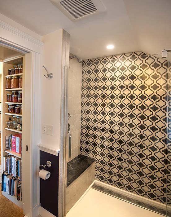 Large walk-in shower with marble-topped bench and intricately patterned tiles on wall
