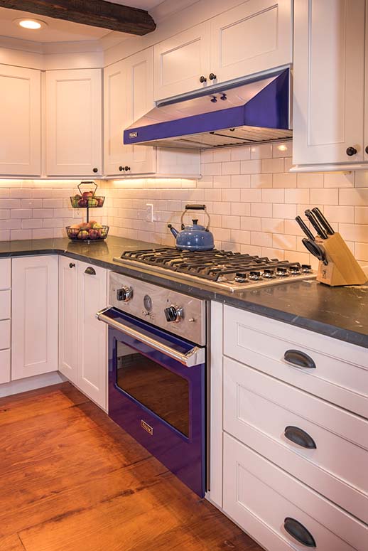 Kitchen remodel with blue oven and range hood, white subway tile backsplash and black marble countertop