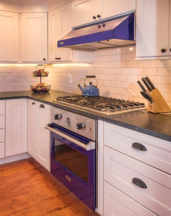 Kitchen remodel with blue oven and range hood, white subway tile backsplash and black marble countertop