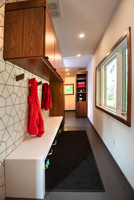 Modern narrow mudroom with geometric tiled wall, bench, and storage built-in