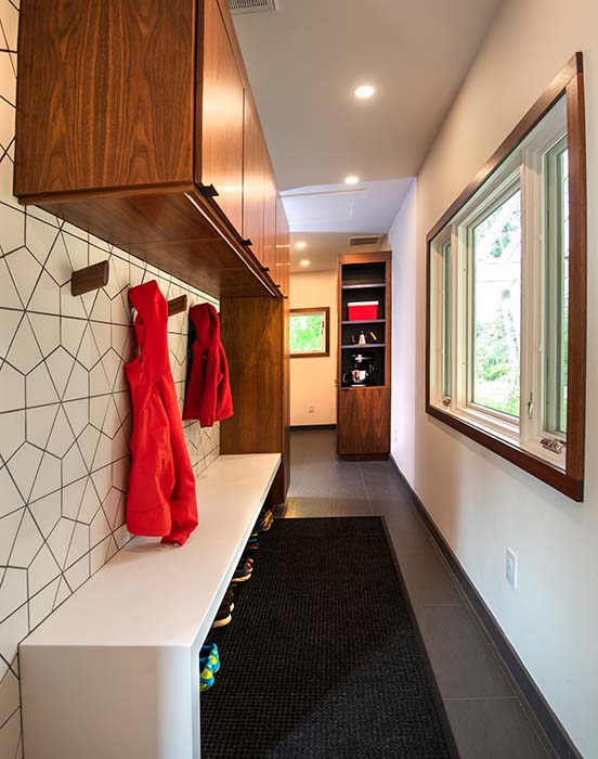 Modern narrow mudroom with geometric tiled wall, bench, and storage built-in