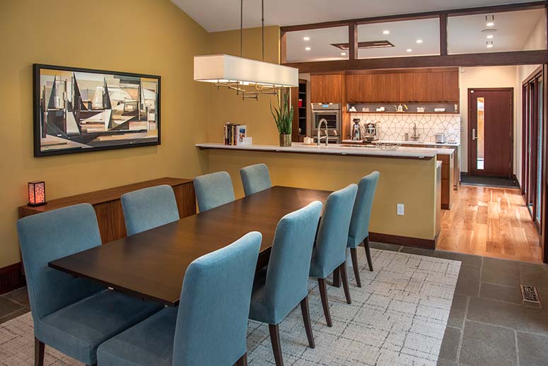 Modern kitchen/dining remodel connected by breakfast bar and wide wood-paneled entryway