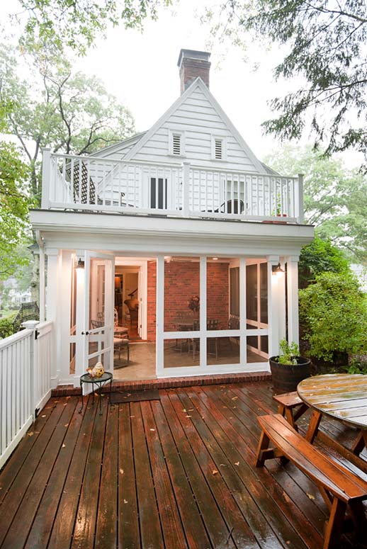 White four seasons/screened porch addition against red brick house exterior, leading onto back deck