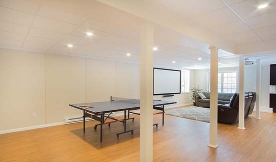 Bright open-plan basement remodel with leather couches, ping pong table, and projector screen