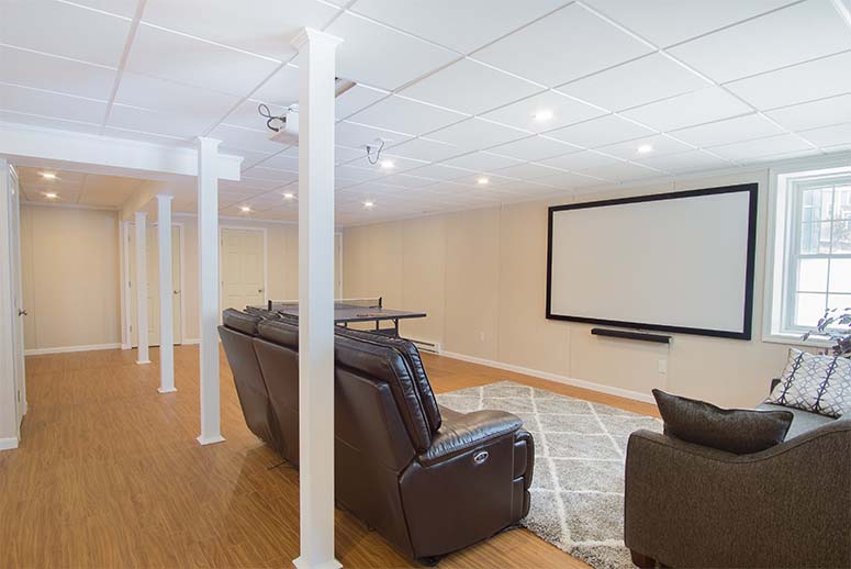 Bright open-plan basement remodel with leather couches, ping pong table, and projector screen