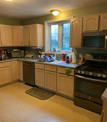 Traditional-looking kitchen with tile floors, light wooden cabinets, and green walls