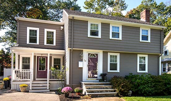 Updated colonial home exterior with two-story addition that includes a front porch and secondary door