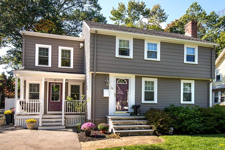 Updated colonial home exterior with two-story addition that includes a front porch and secondary door