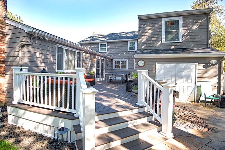 Deck behind home with couches and hanging lights