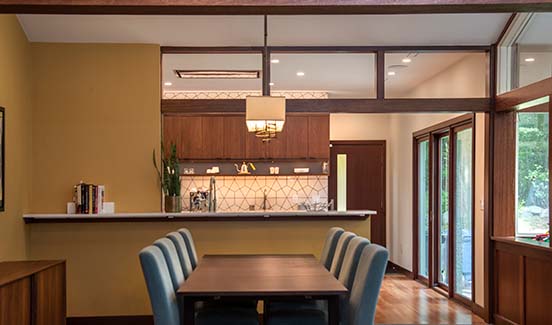 Modern kitchen/dining remodel connected by breakfast bar and wide wood-paneled entryway