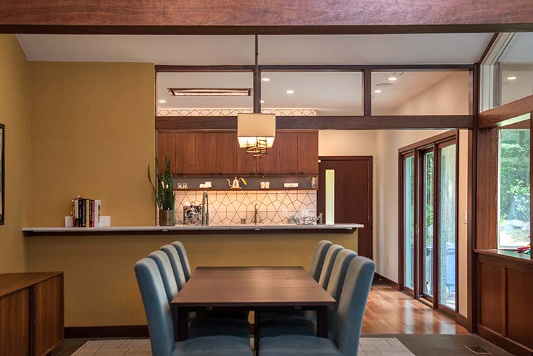 Modern kitchen/dining remodel connected by breakfast bar and wide wood-paneled entryway