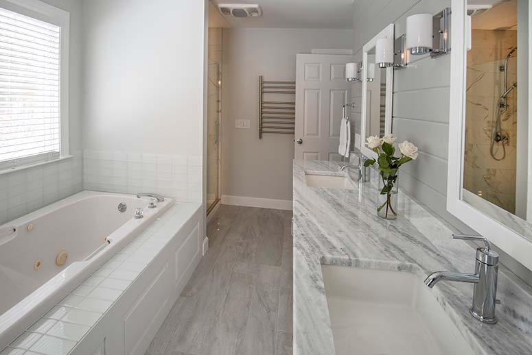 Remodeled bathroom with grey shiplap accent wall, grey walls, and granite double vanity