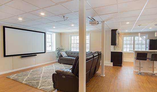 Bright open-plan basement remodel with leather couches, ping pong table, and projector screen