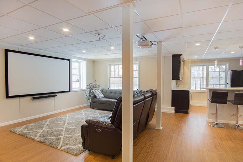 Bright open-plan basement remodel with leather couches, ping pong table, and projector screen