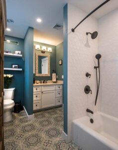 Bathroom remodel with boho-patterned black and white tiled floor and dark teal walls 