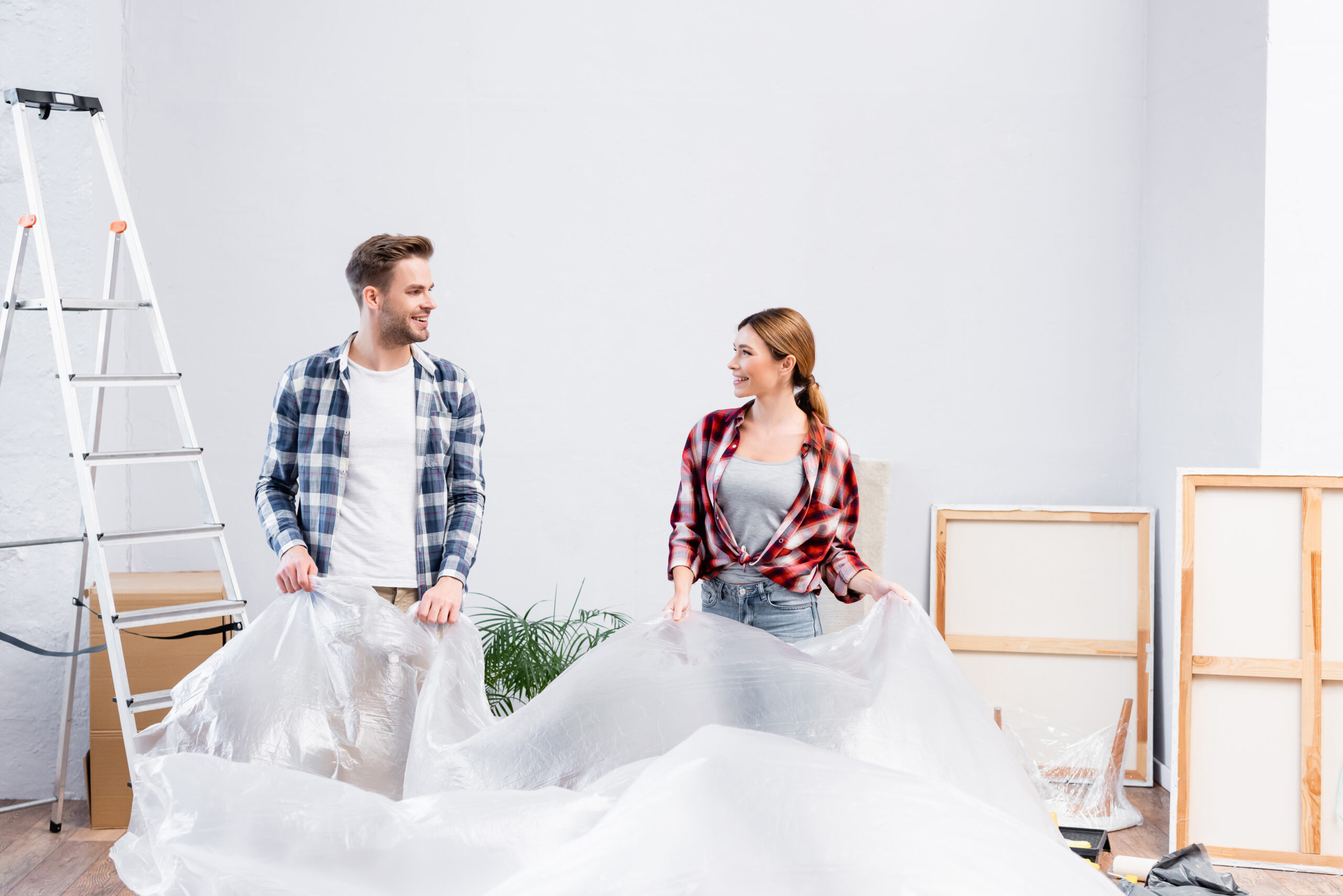 Two people moving into their home with packing material