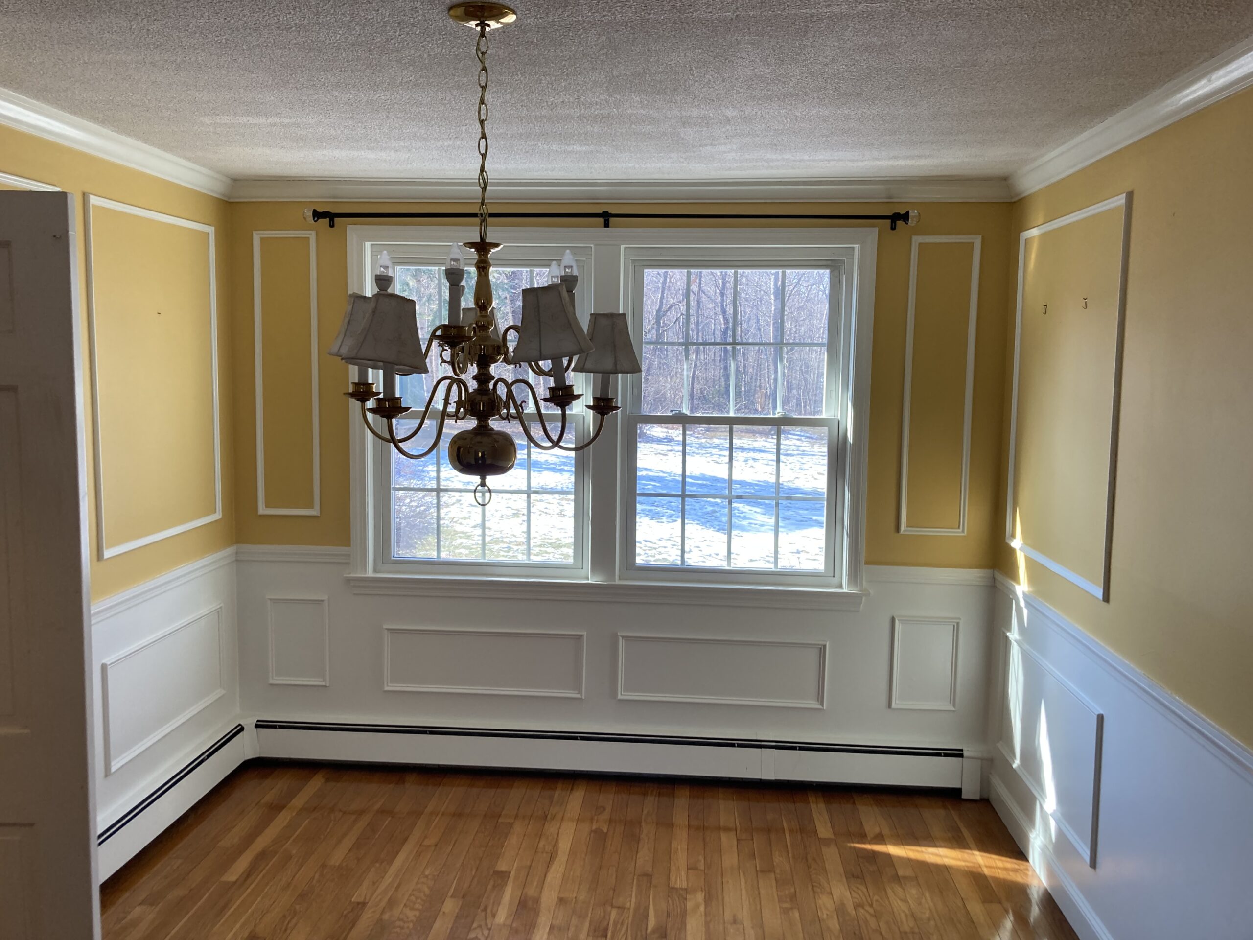 Unfurnished dining room with yellow painted walls and a gold chandelier
