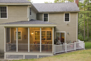 Screened in porch on the back of a large two-story tan home.