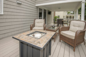 outdoor fireplace and two patio chairs on a deck.